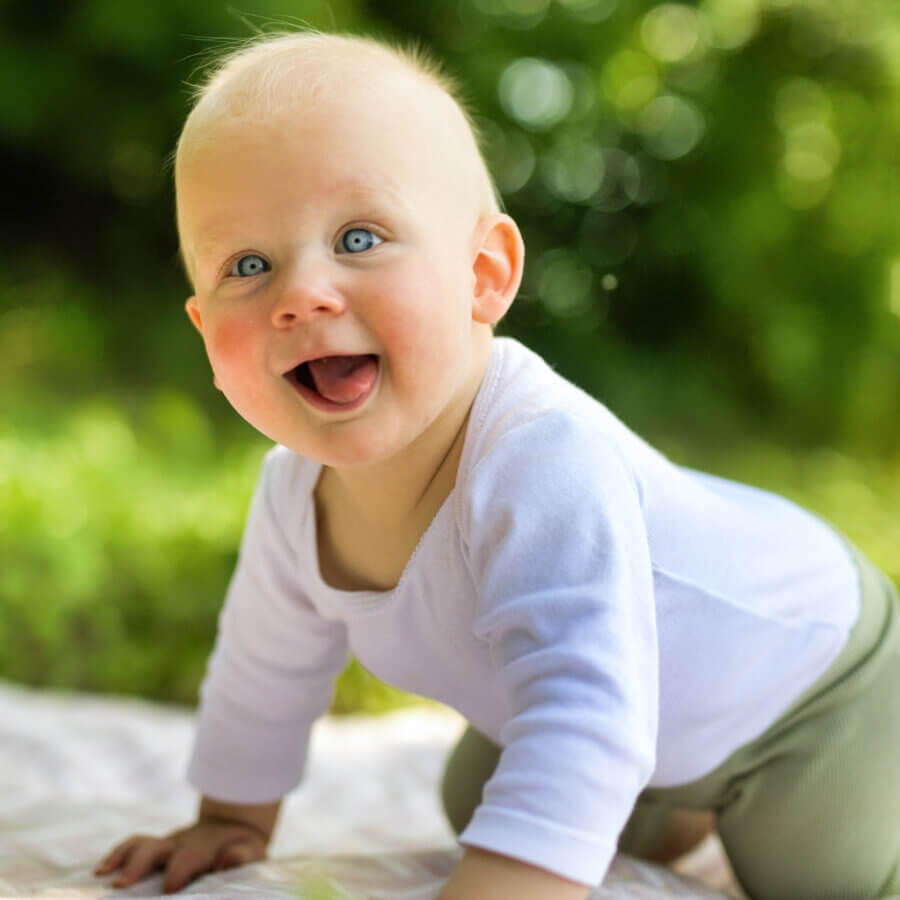 Baby auf allen Vieren mit geöffnetem Mund und grossen leuchtenden Augen